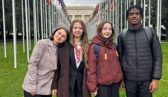 Some of the youth advocates posing in front of the alley of flags of the Palais des Nations in Geneva