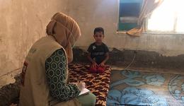 Corona response War Child_ employee helps child with mask_War Child Iraq_200603